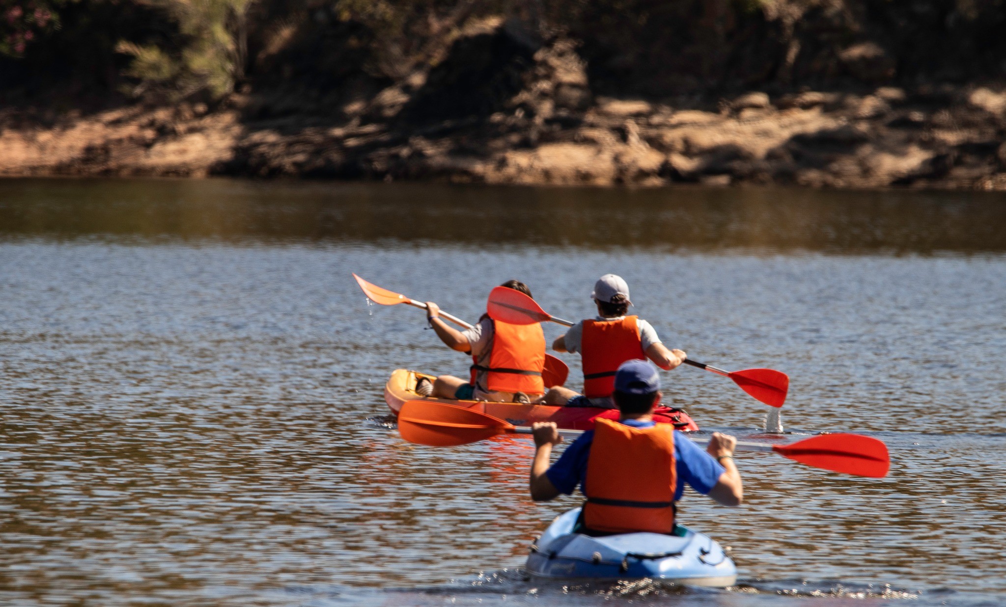 Tres personas remando en kayak sobre un lago.