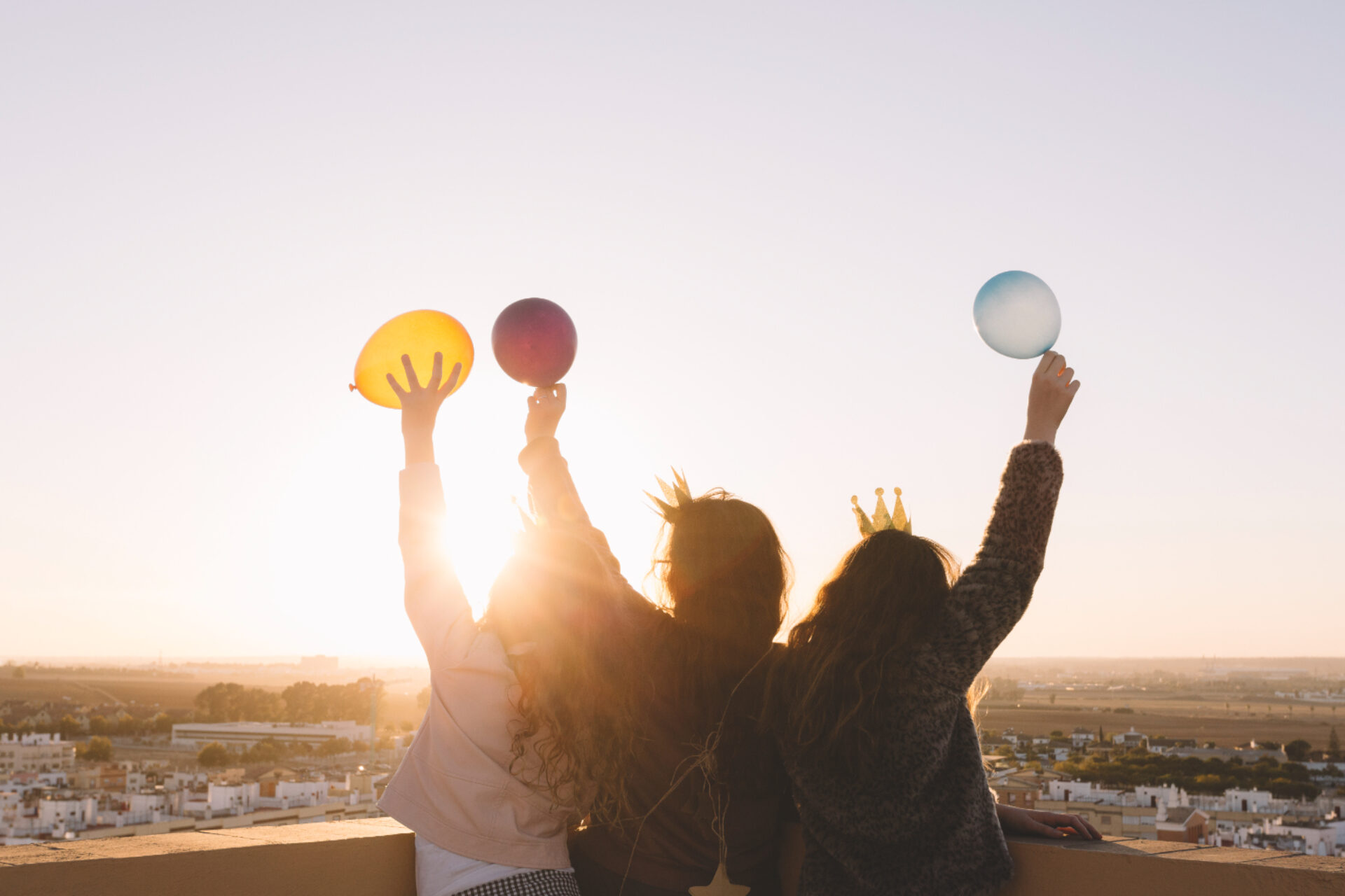 Amigos celebrando un cumpleaños al atardecer con globos, disfrutando de un momento especial al aire libre.