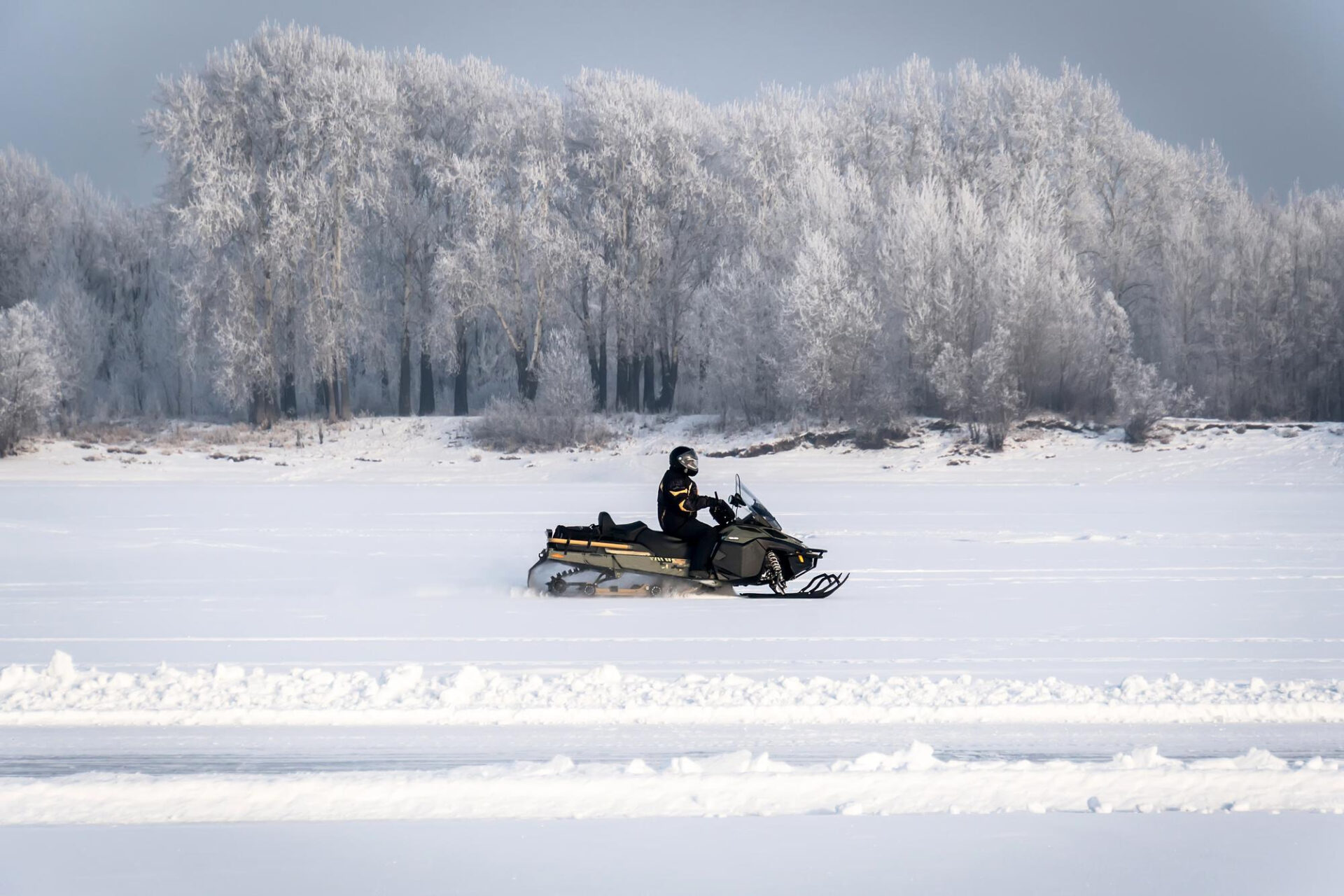 Persona conduciendo una moto de nieve en un paisaje de montaña cubierto de nieve en invierno