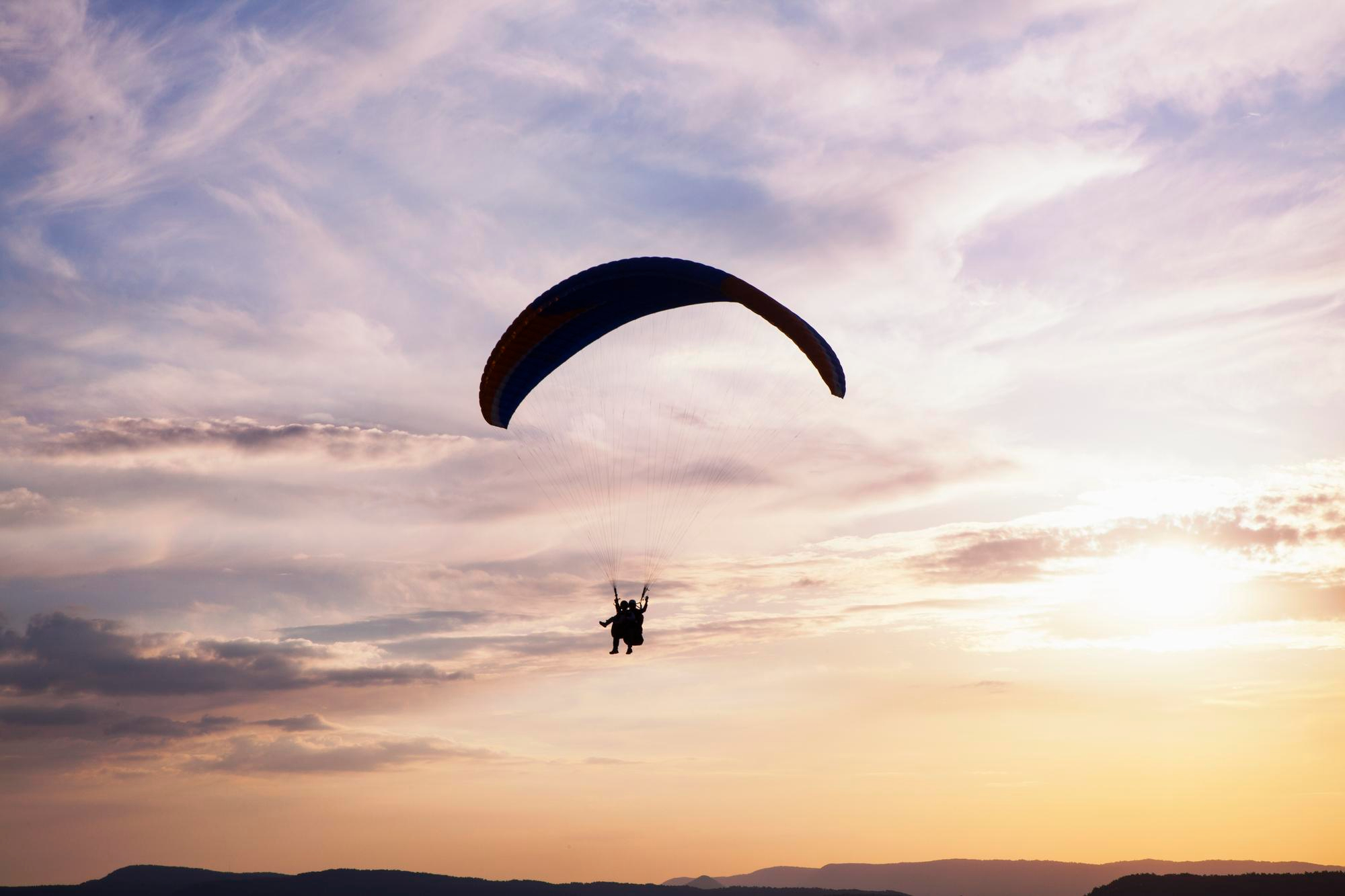 Parapente volando sobre la costa con vistas al mar y los acantilados naturales