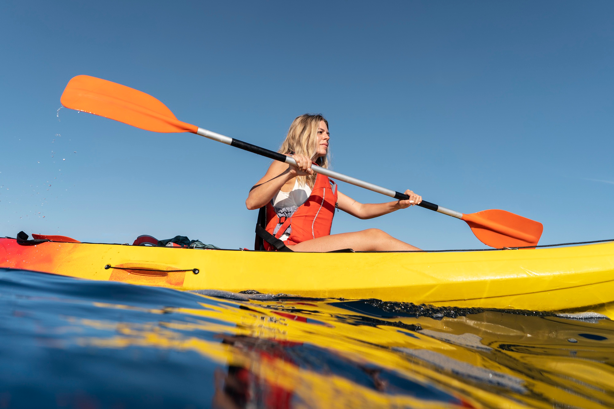 Mujer practicando kayak en el mar como actividad de aventura al aire libre