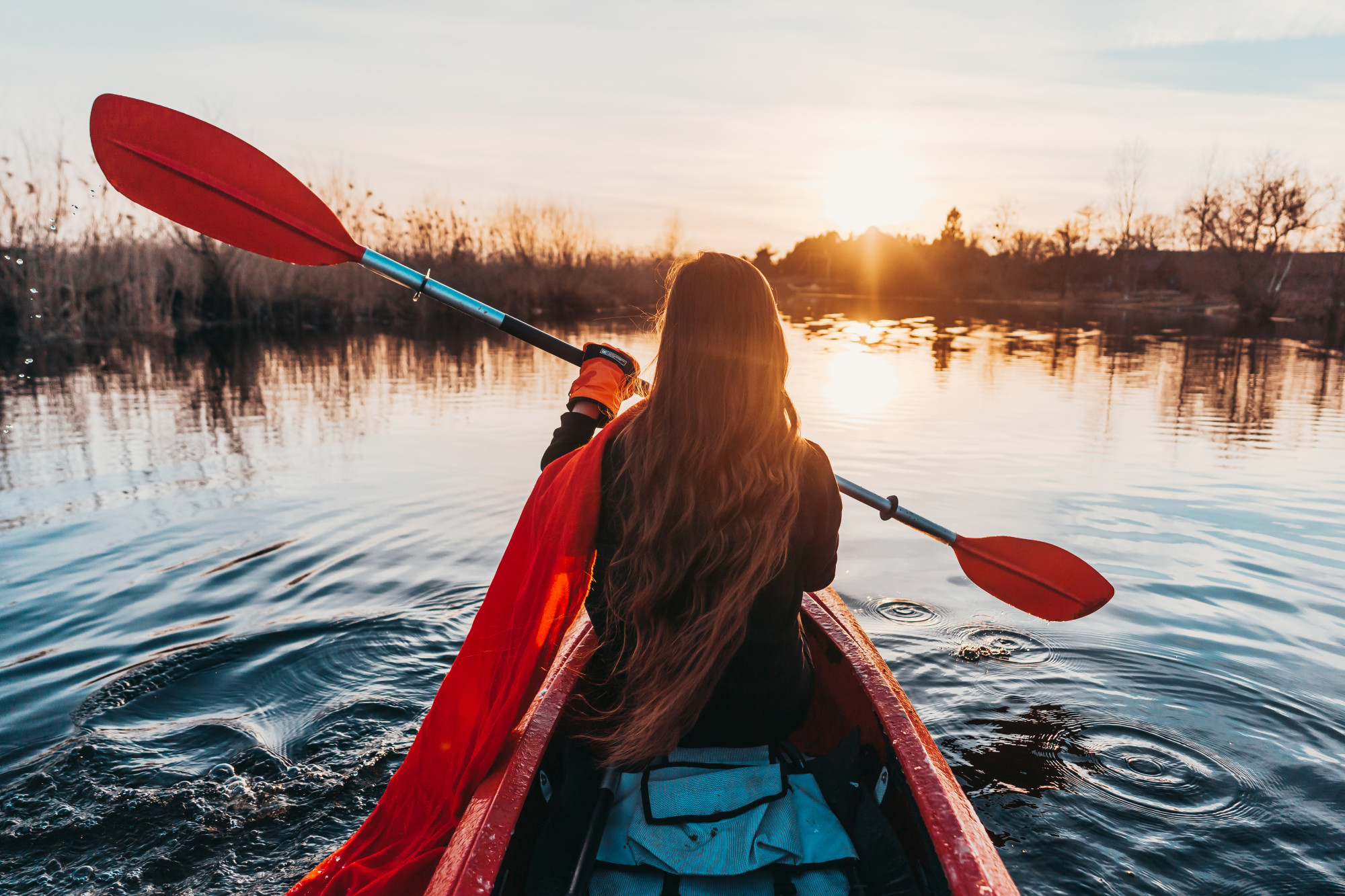 Persona practicando kayak al atardecer en un entorno natural tranquilo