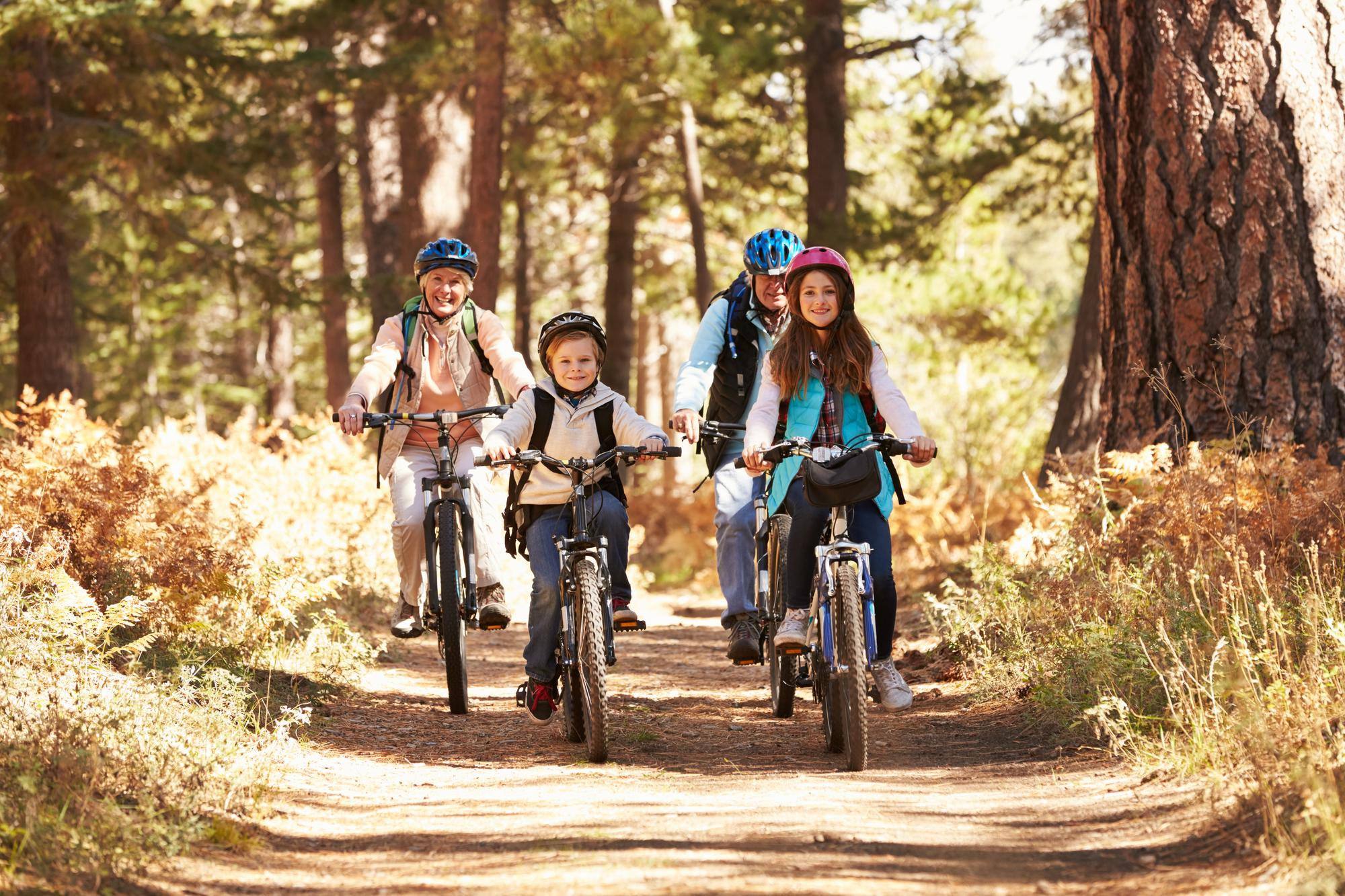 Familia practicando ciclismo juntos en un bosque como actividad al aire libre y de aventura