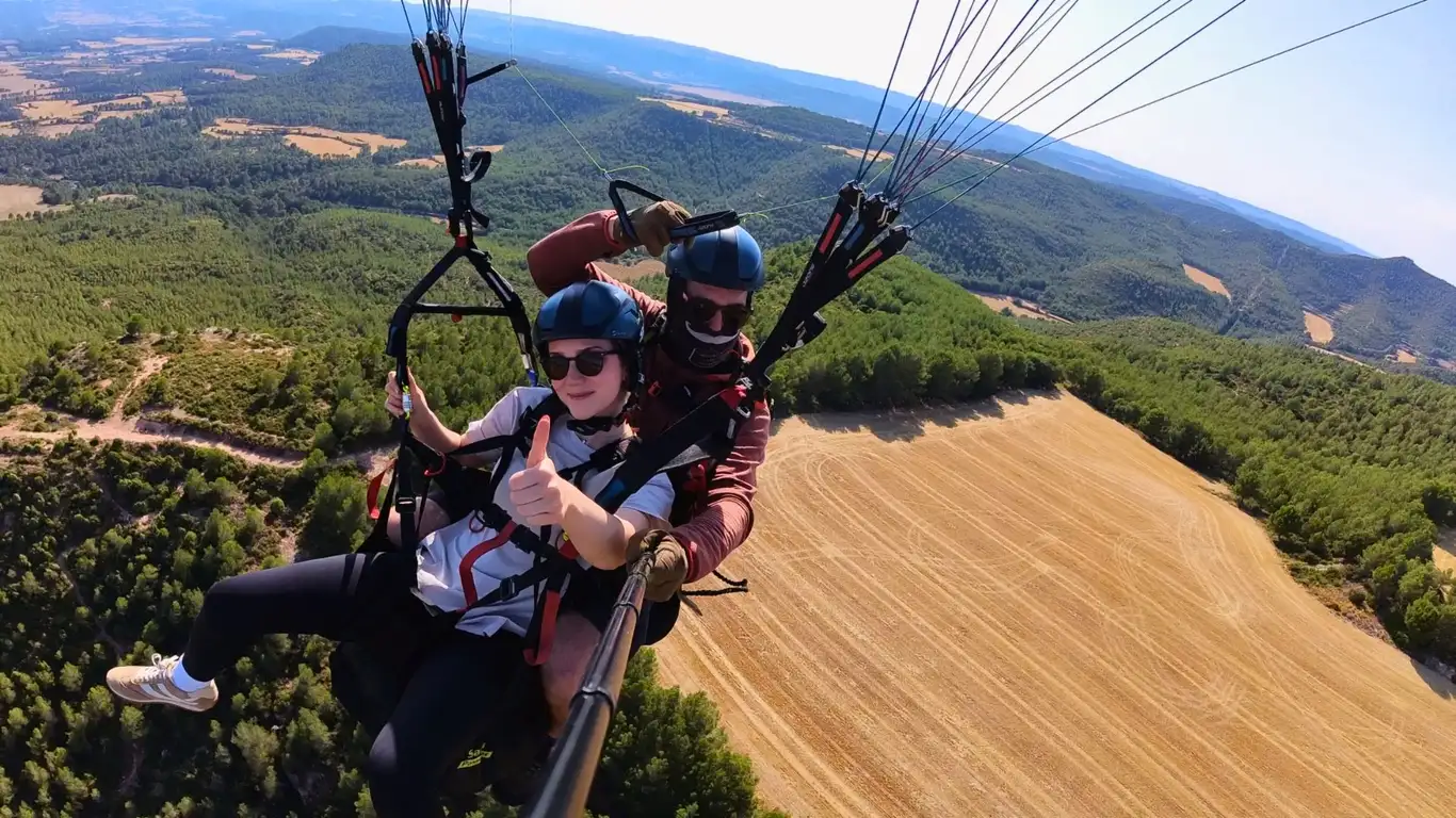 Personas realizando un vuelo en parapente biplaza sobre un paisaje natural desde el aire