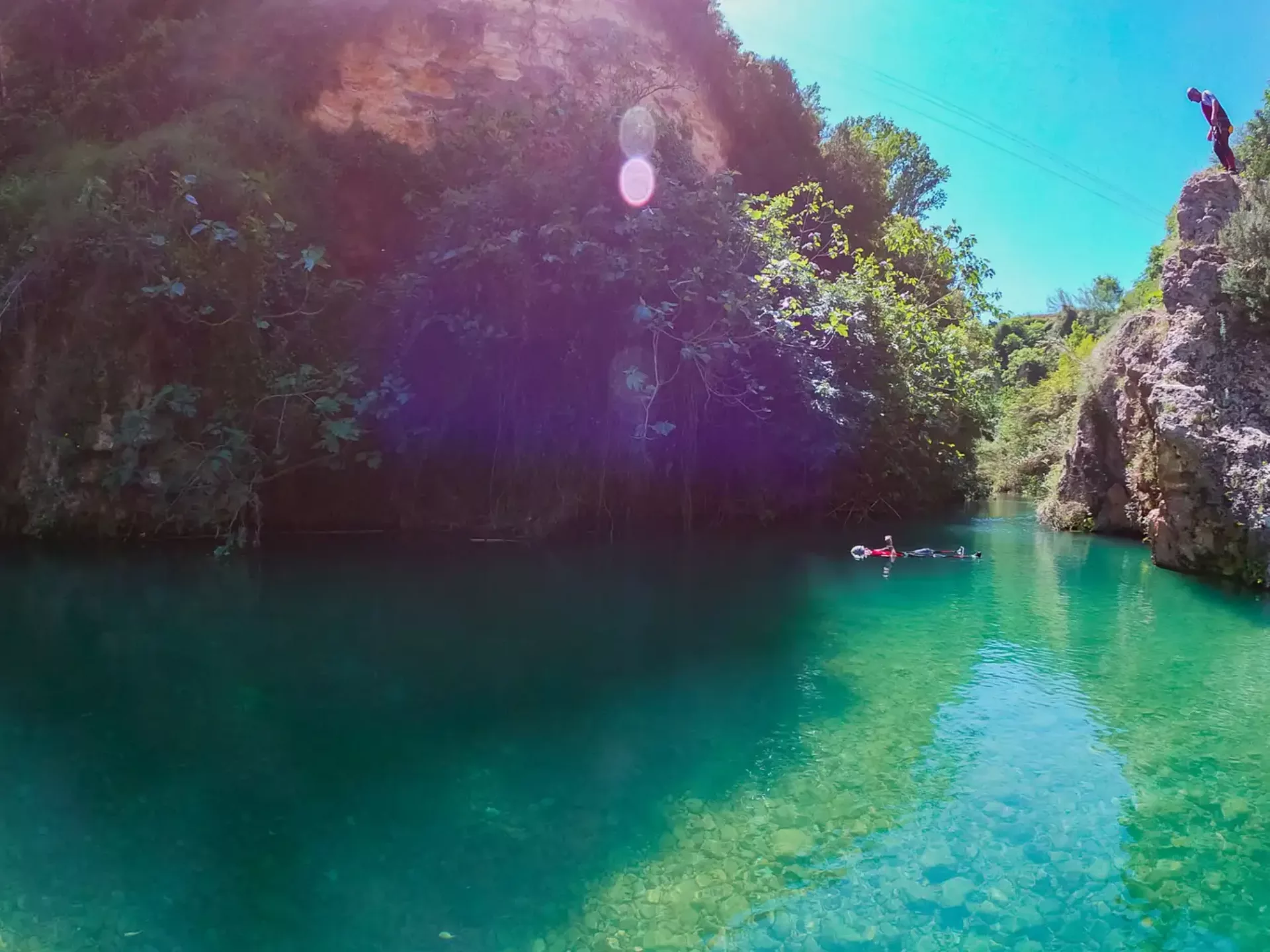 Persona practicando canyoning saltando a una poza de agua cristalina en un entorno natural