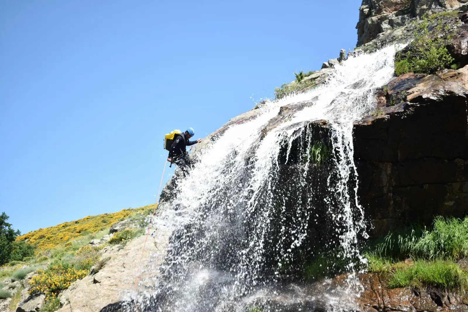 Persona practicando barranquismo descendiendo una cascada en un entorno natural
