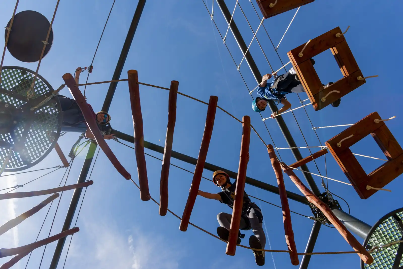 Personas realizando un circuito de aventura en altura en un parque de actividades al aire libre