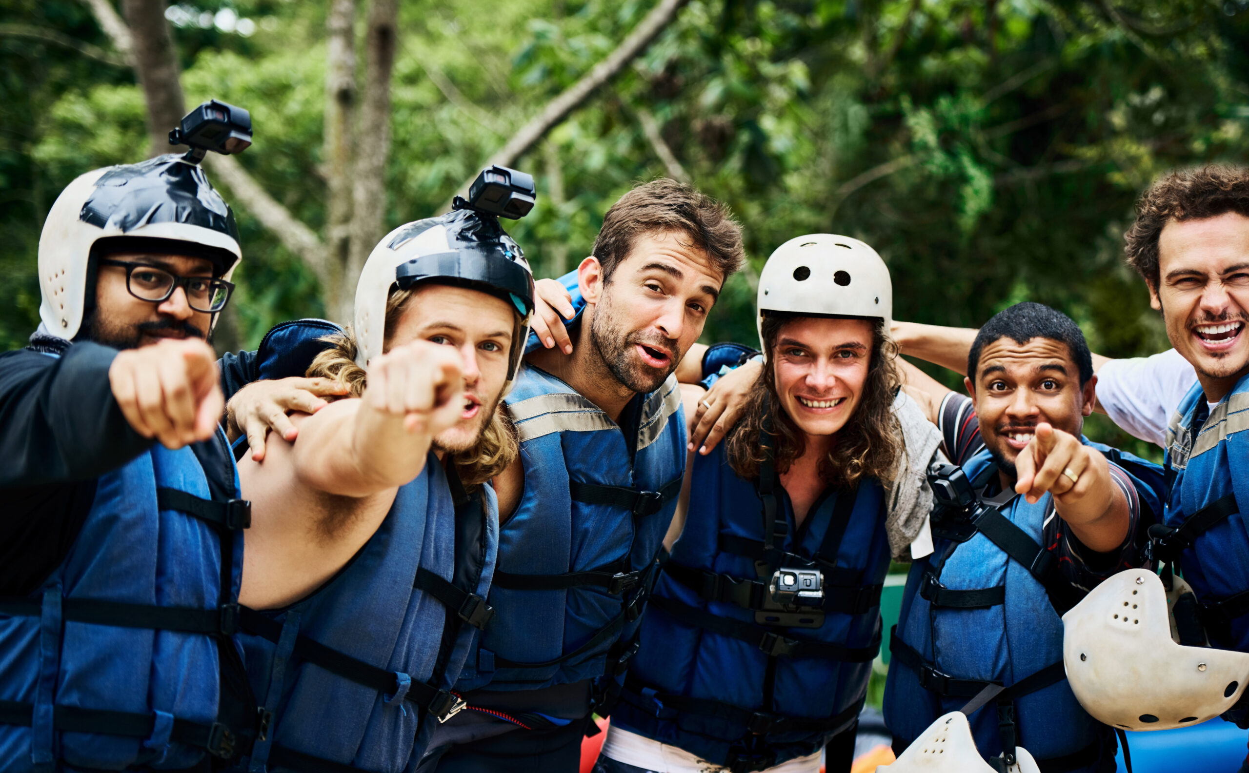 Grupo de personas equipadas para hacer rafting posando juntas antes de una actividad de aventura en la naturaleza