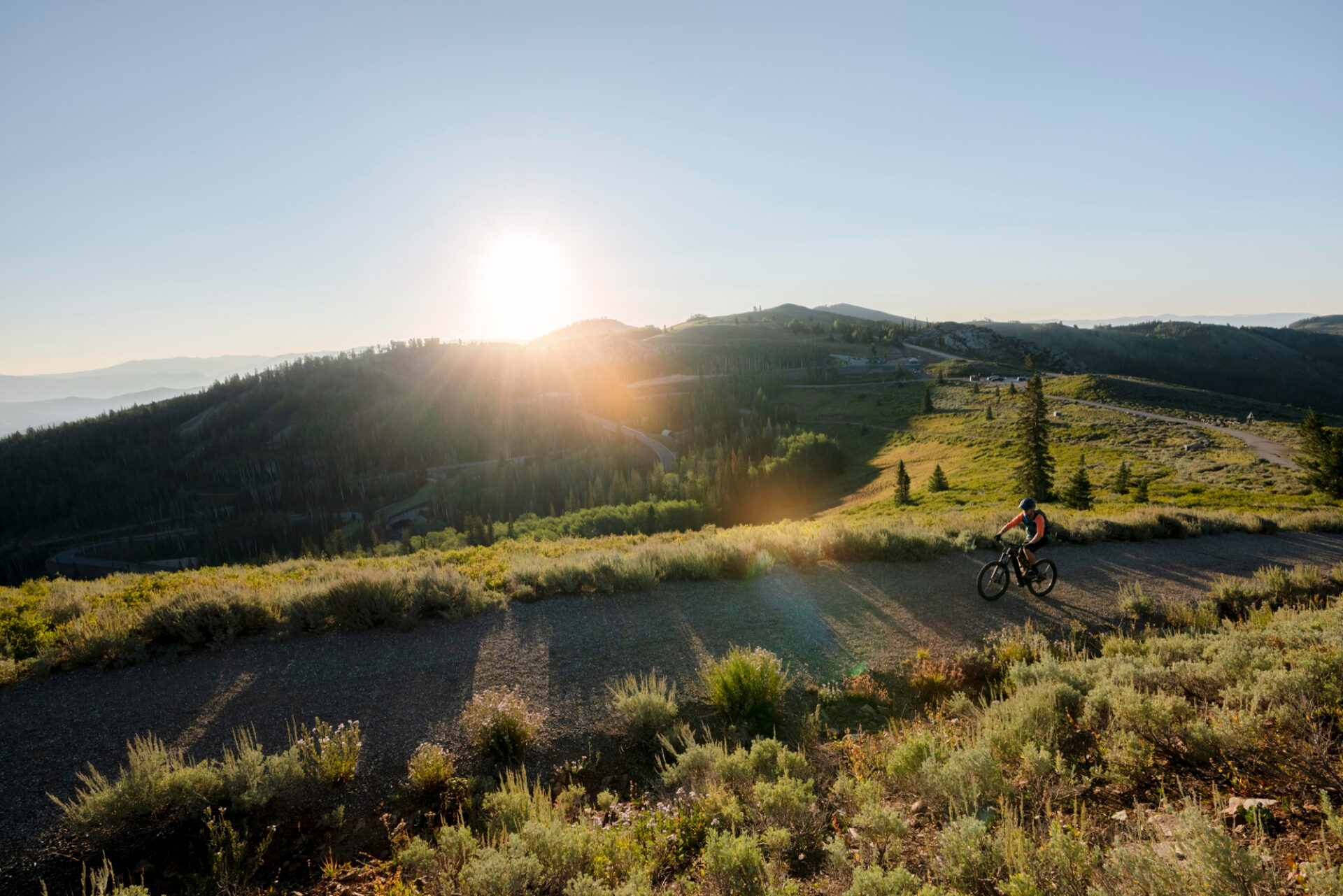 Ciclista recorriendo un sendero de montaña al atardecer, disfrutando de una experiencia de aventura en plena naturaleza.