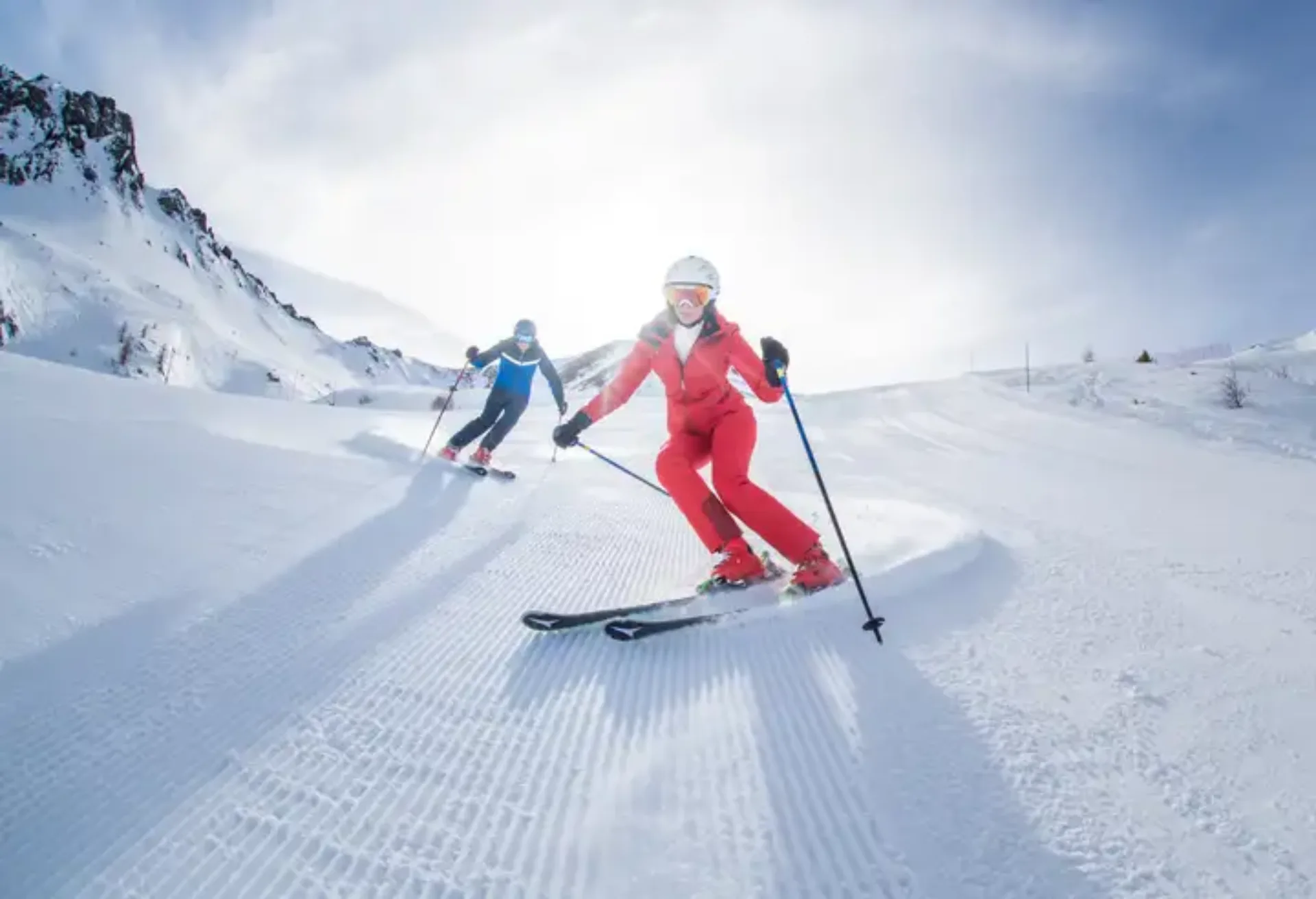 Dos personas aprendiendo a esquiar en una pista nevada, siguiendo una clase de esquí para mejorar la tecnica y ganar confianza en la montaña