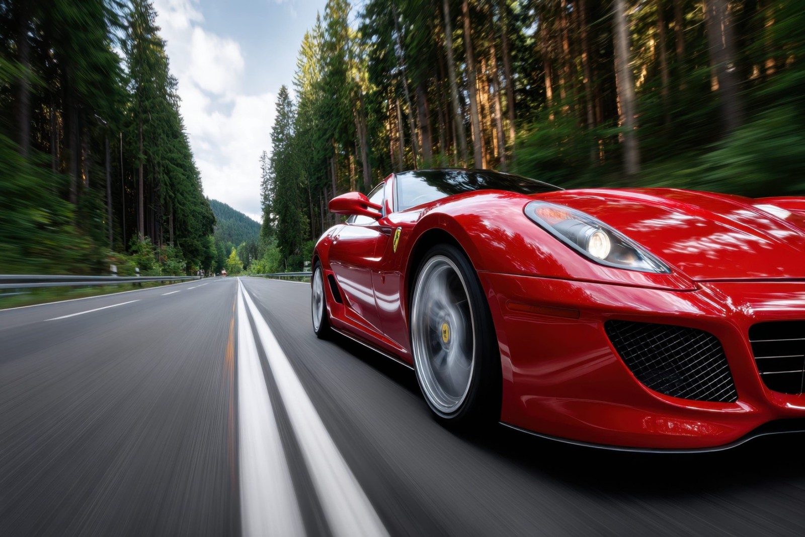 Coche deportivo rojo conduciendo a alta velocidad por una carretera rodeada de bosque y montanas