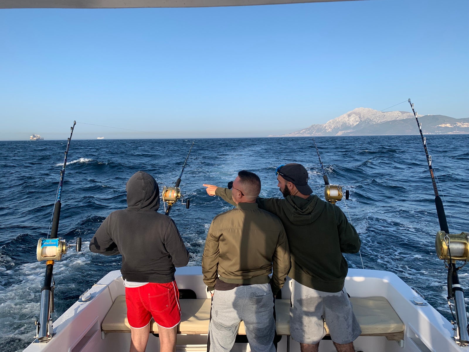 Grupo de amigos disfrutando de una jornada de pesca deportiva a bordo de un barco en alta mar.
