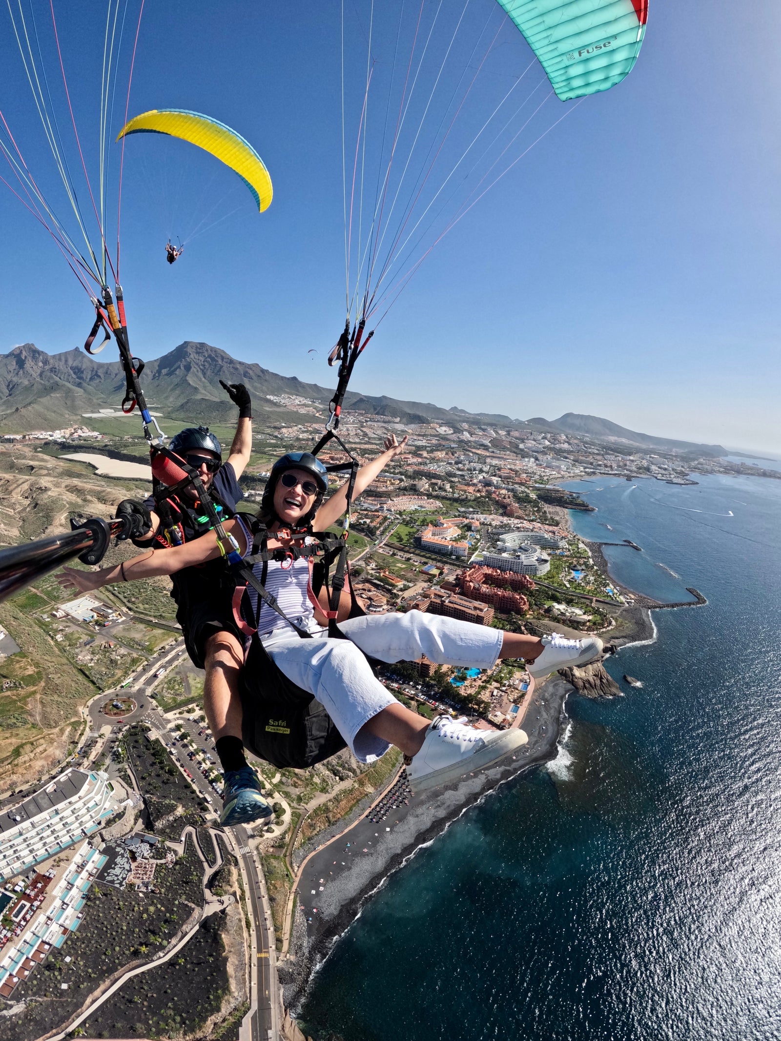 Una vista aérea de ojo de pez de una pareja haciendo parapente en tándem sobre la costa de islas Canarias